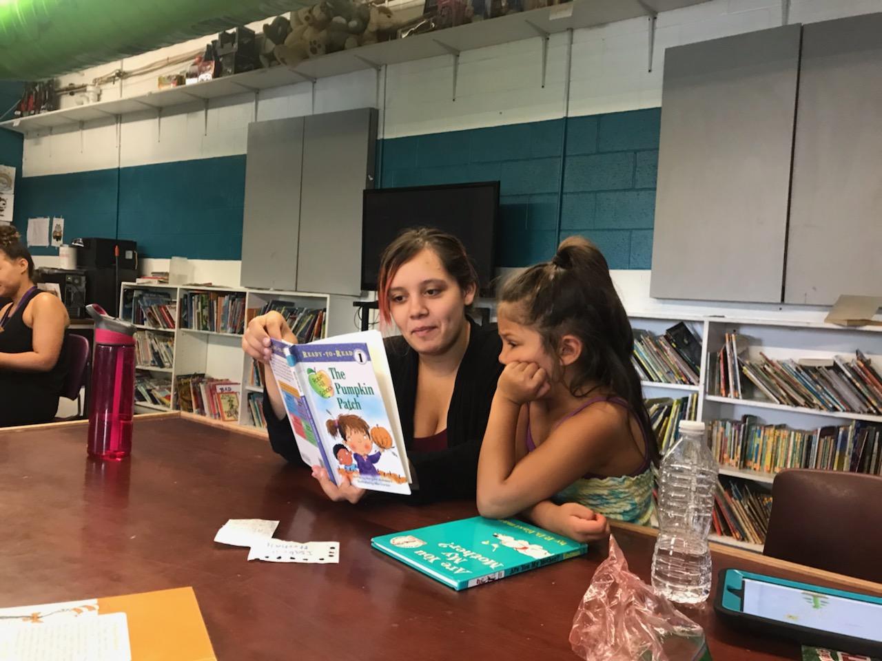 Woman reading book with young girl at library.