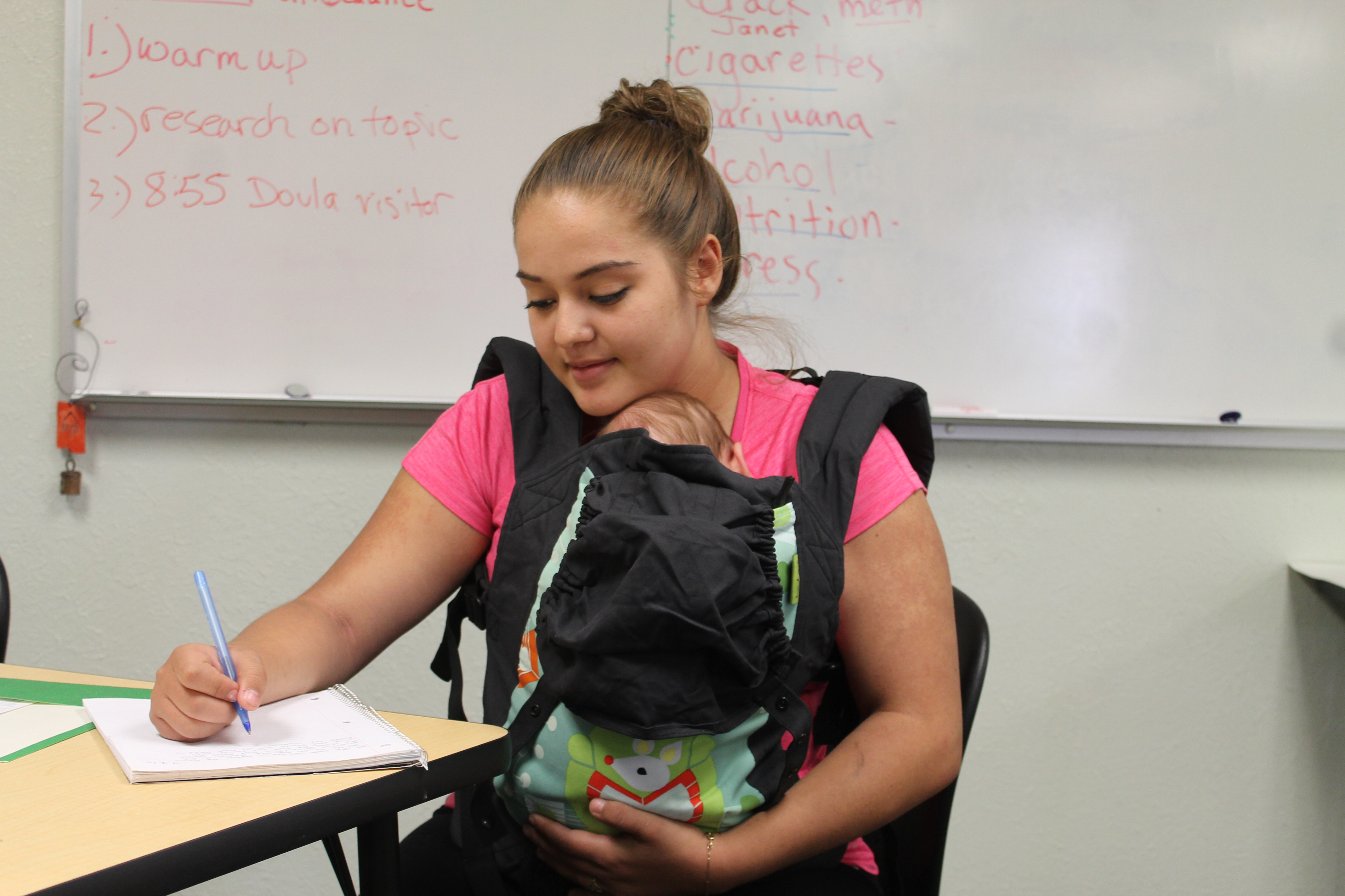 Young woman studying with baby in sling