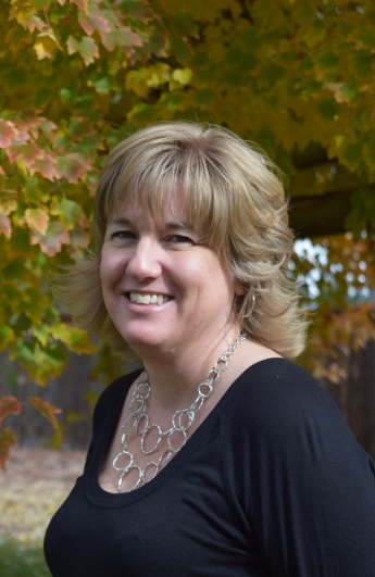 Woman smiling in autumn leaves backdrop.