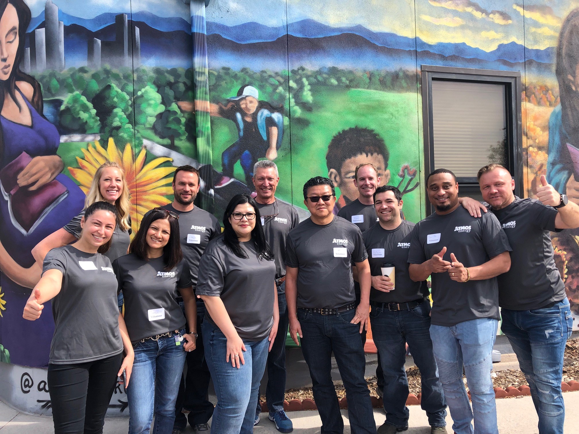 Group of people smiling in front of mural.