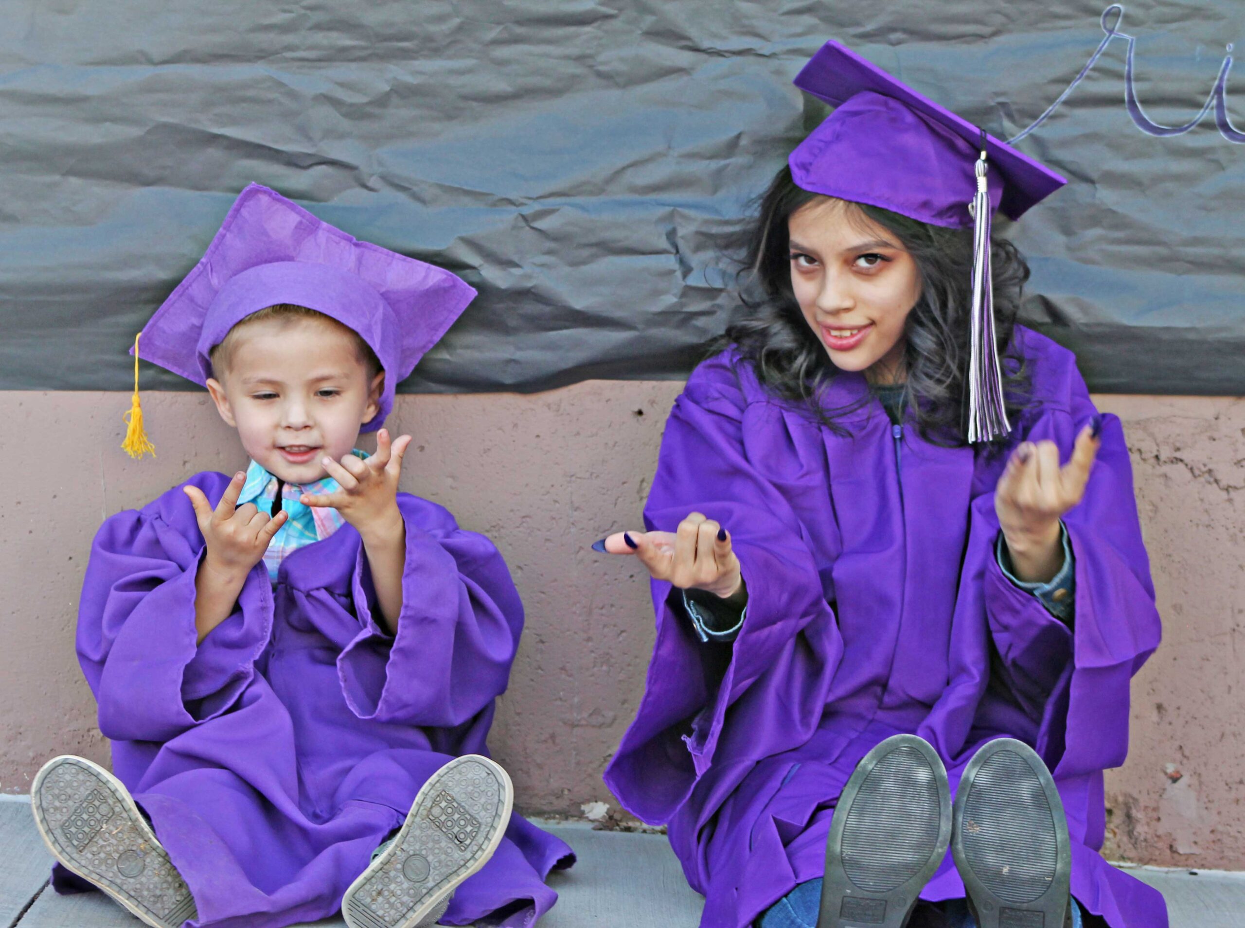 Woman and child in graduation gowns posing happily.