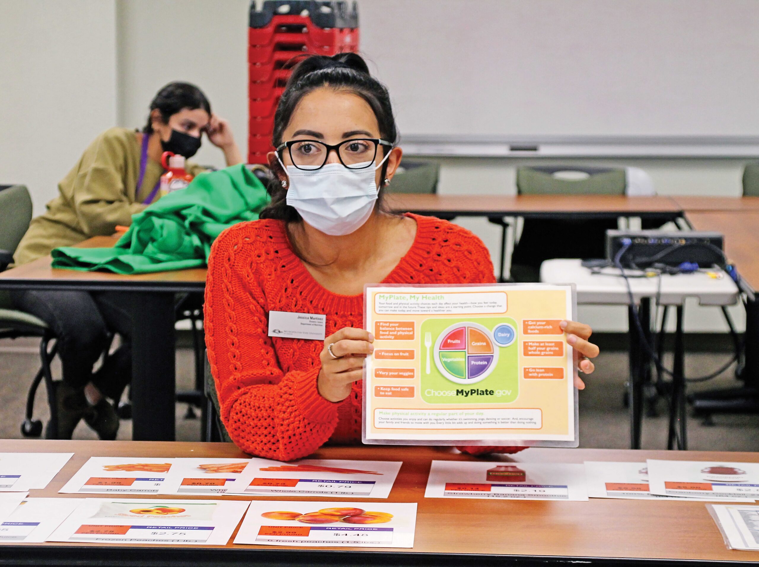 Instructor explaining MyPlate nutrition chart in classroom.