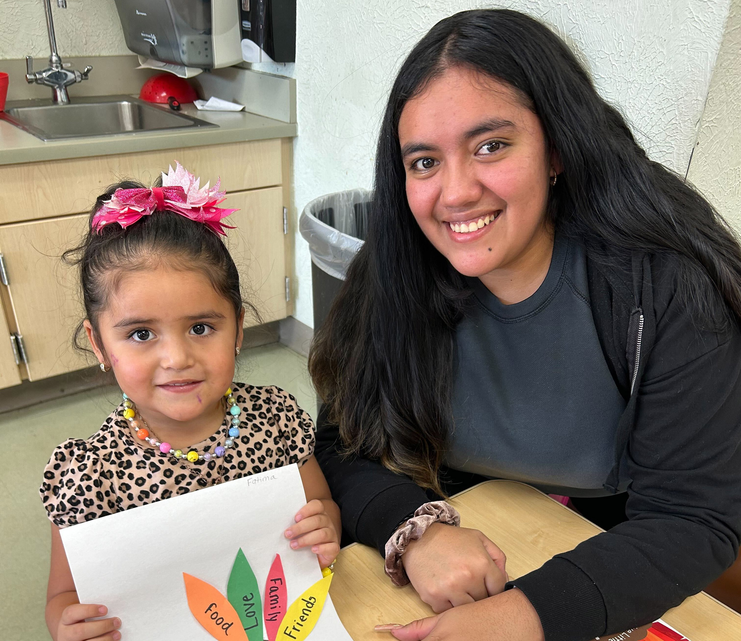 Smiling child and adult with Thanksgiving craft