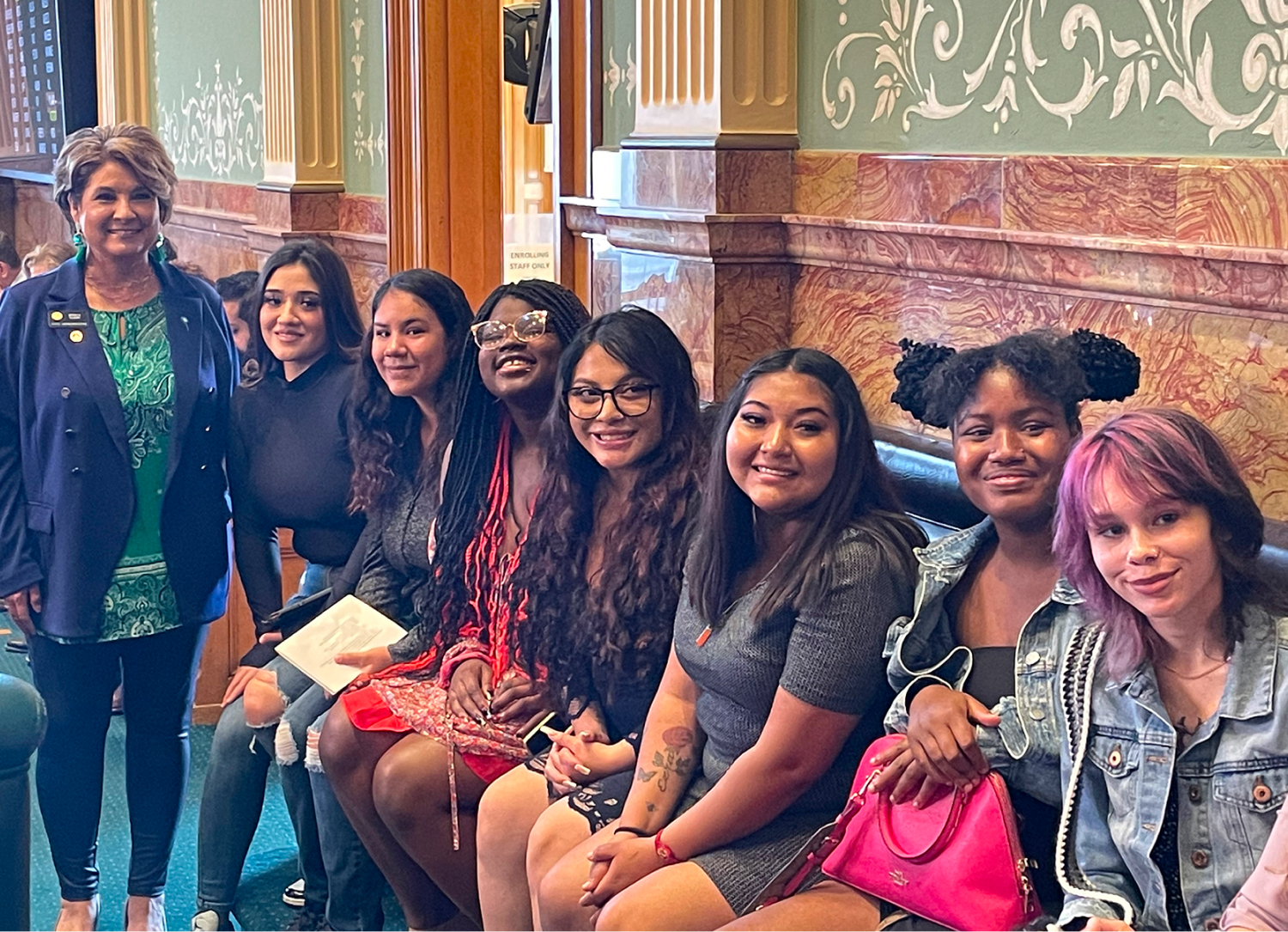 Group of women smiling indoors, sitting on bench.