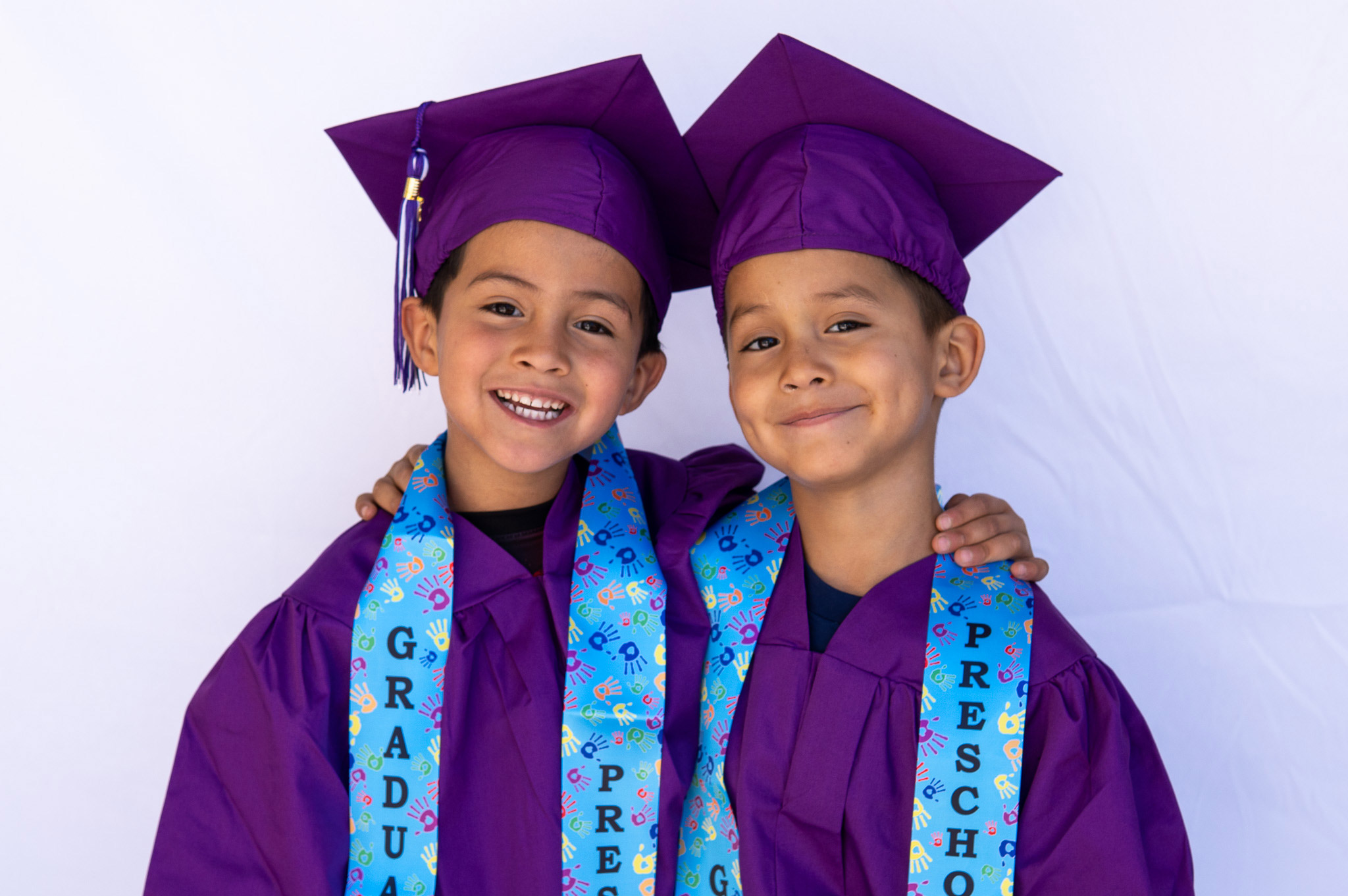 Two boys in graduation caps smiling together.