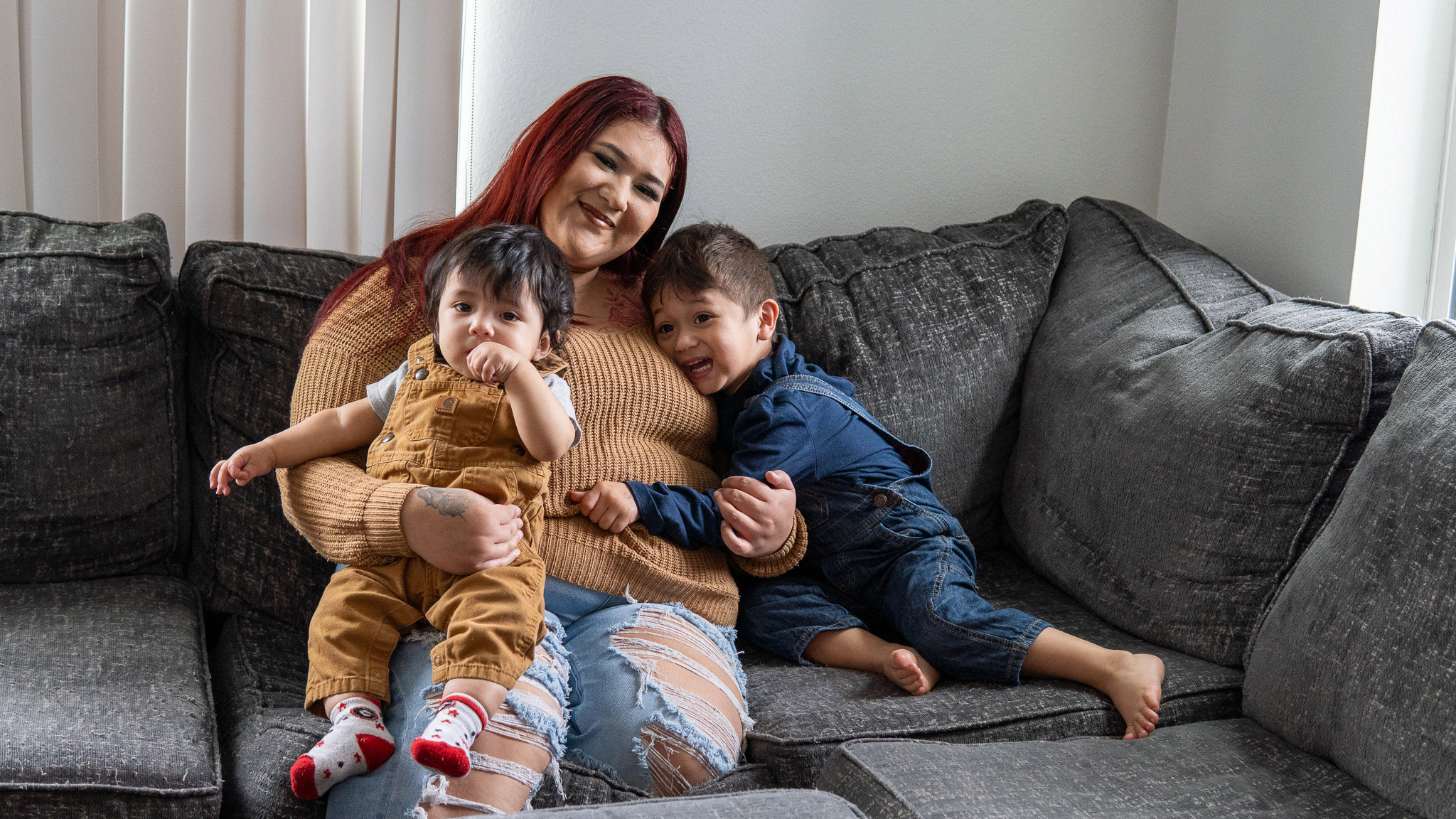 Smiling mother and two kids on a sofa.