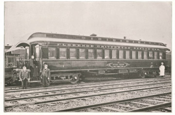 Historic train car with people standing nearby.