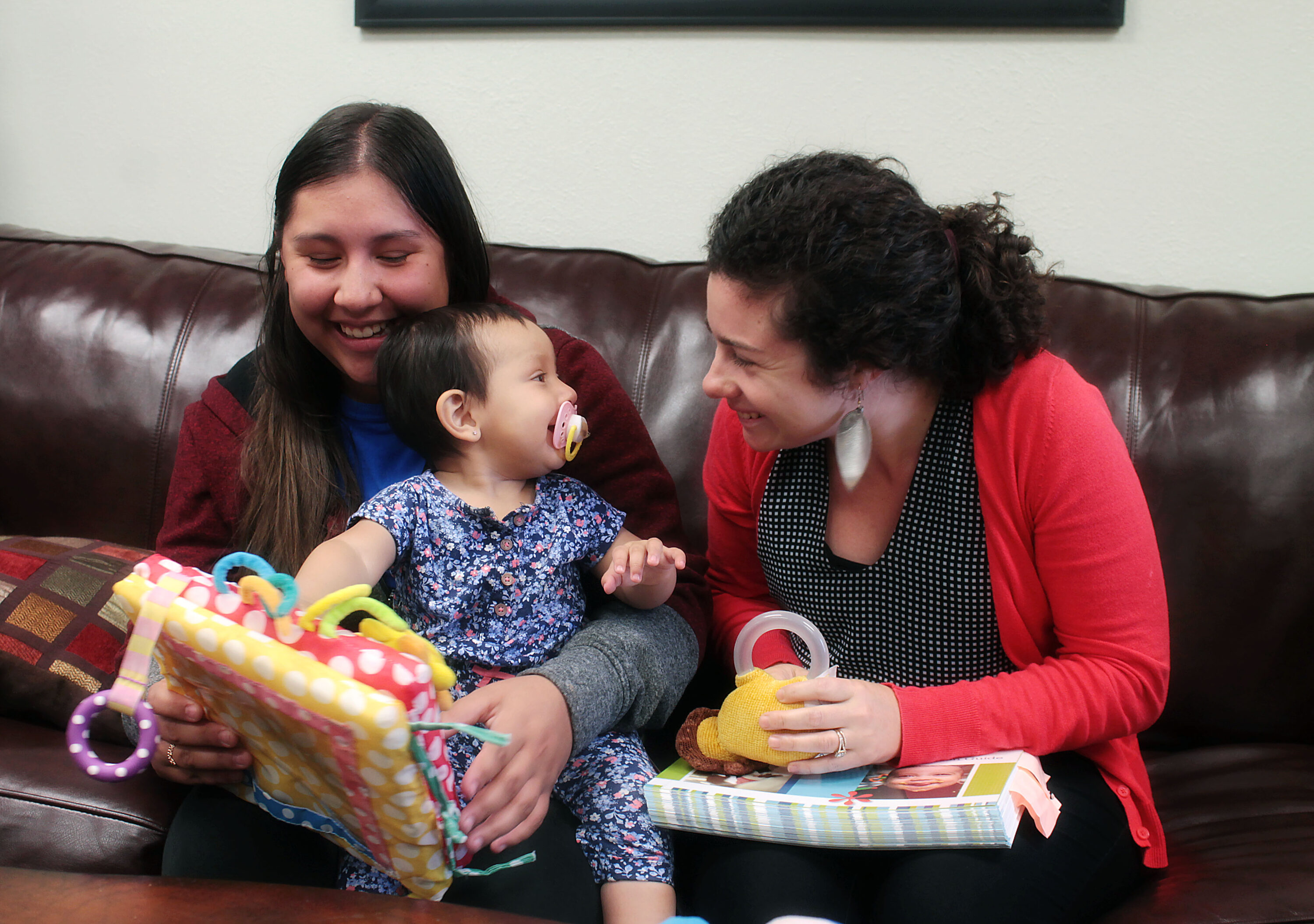 Women smiling with baby on couch