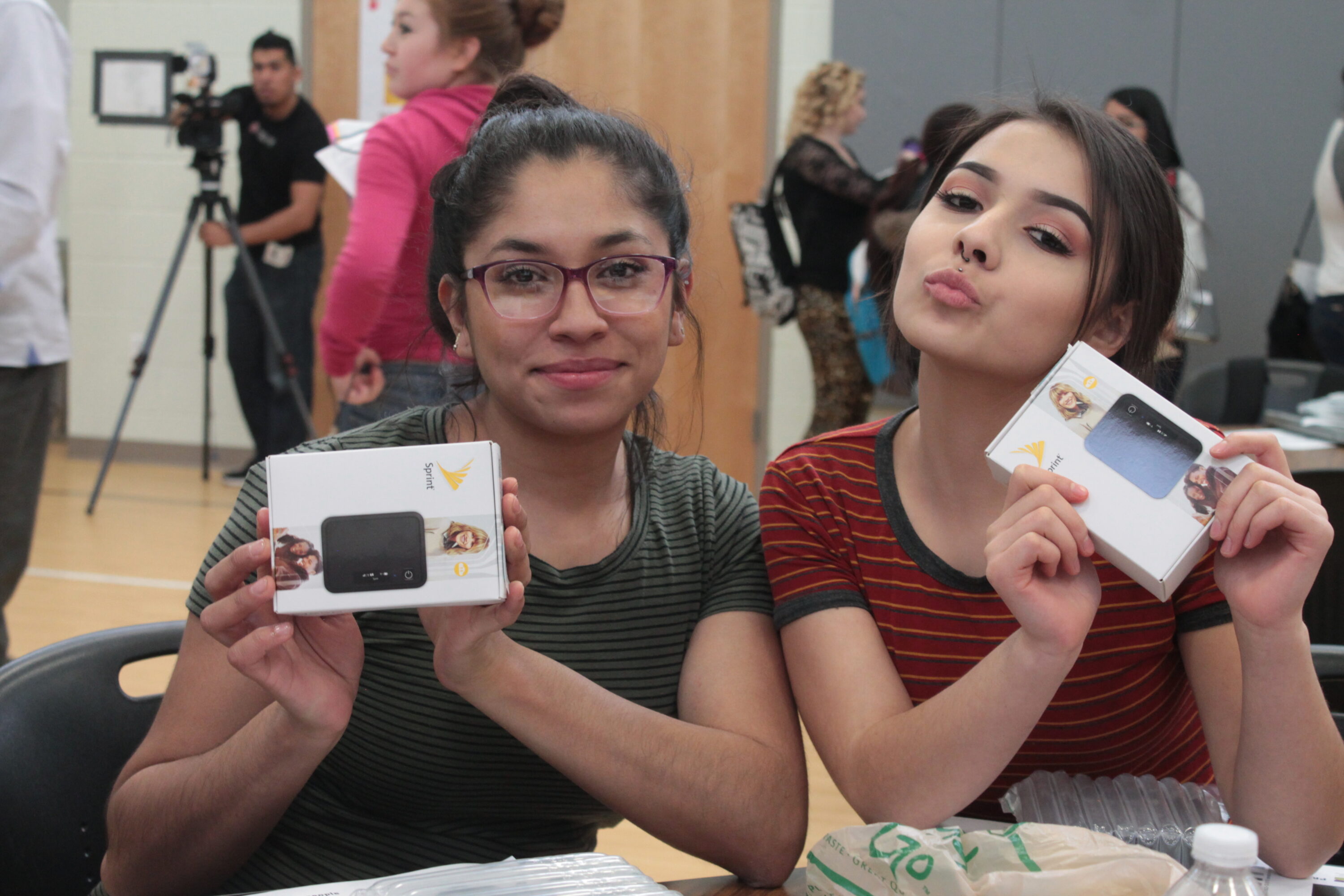 Two women holding Sprint device boxes.