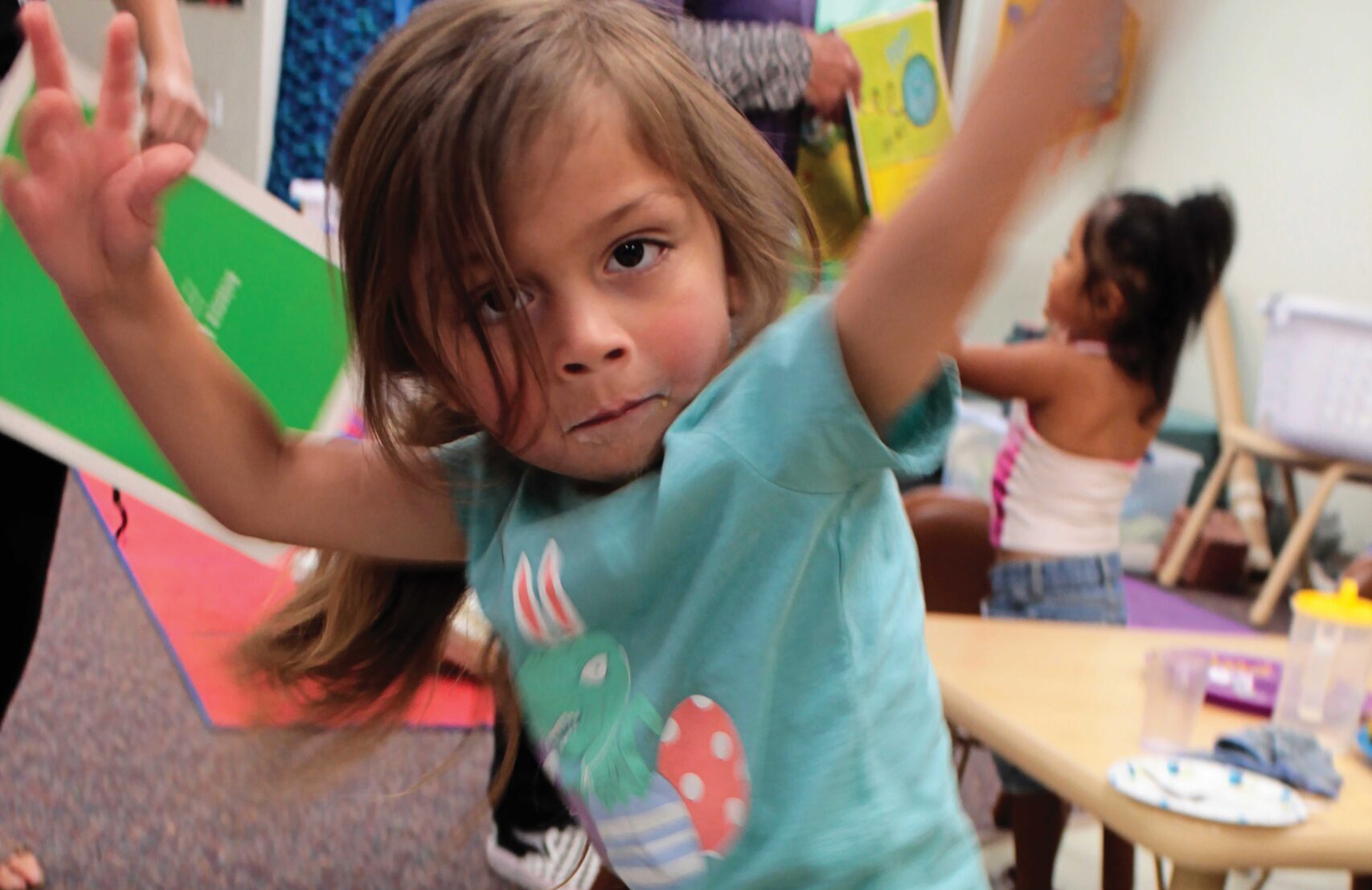 Child playing energetically in a classroom setting.