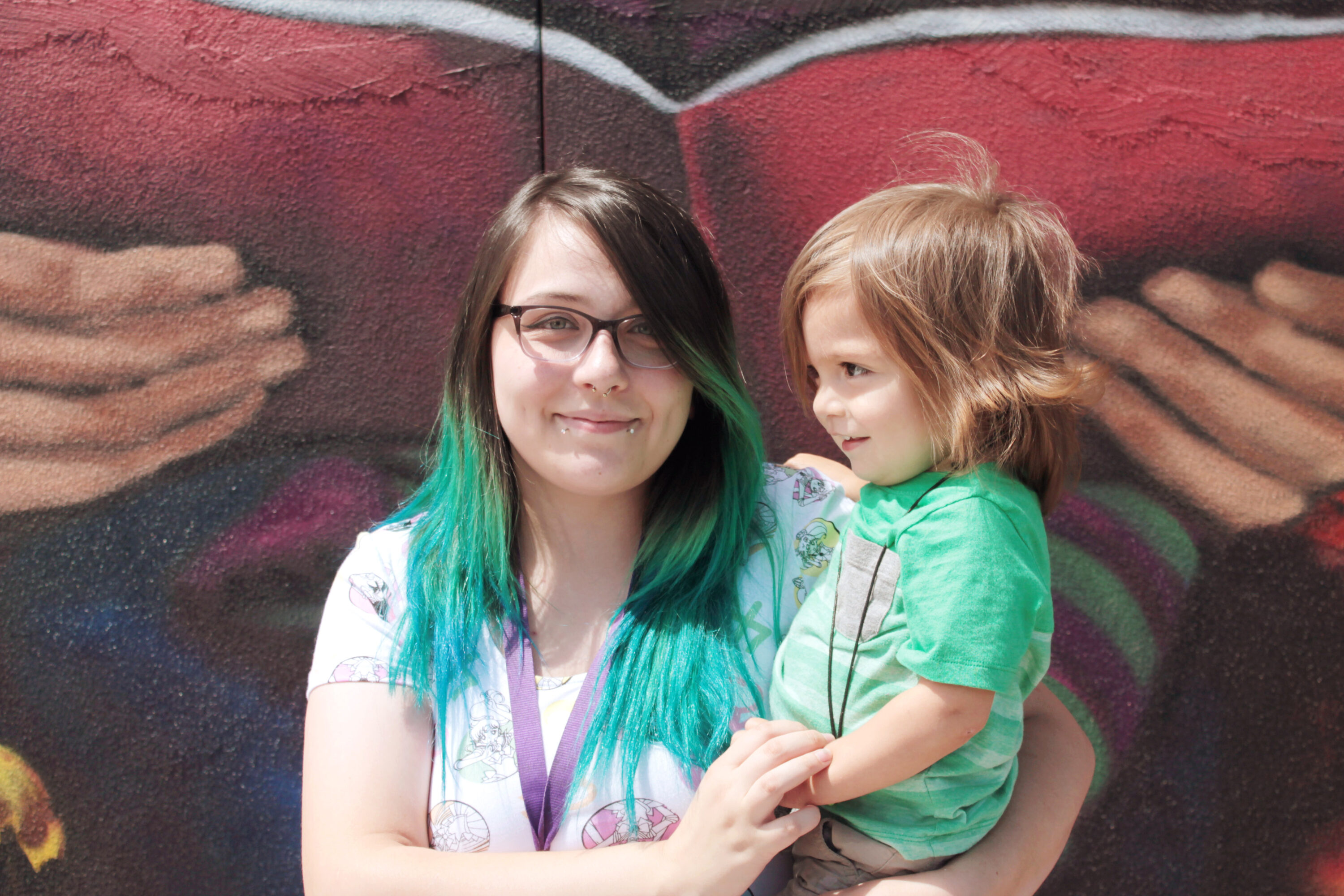 Woman with child in front of colorful mural.