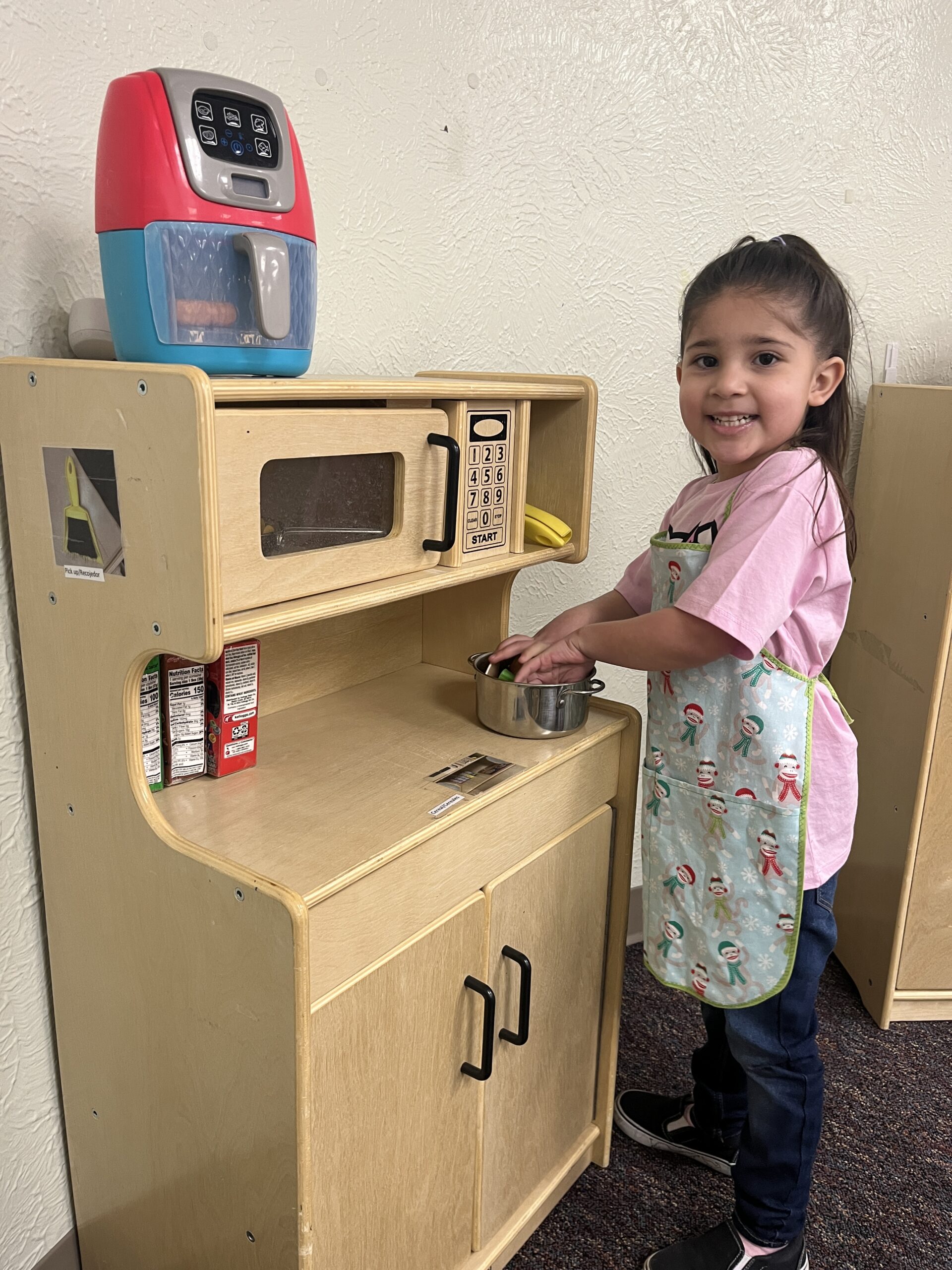 Child playing in a toy kitchen with apron