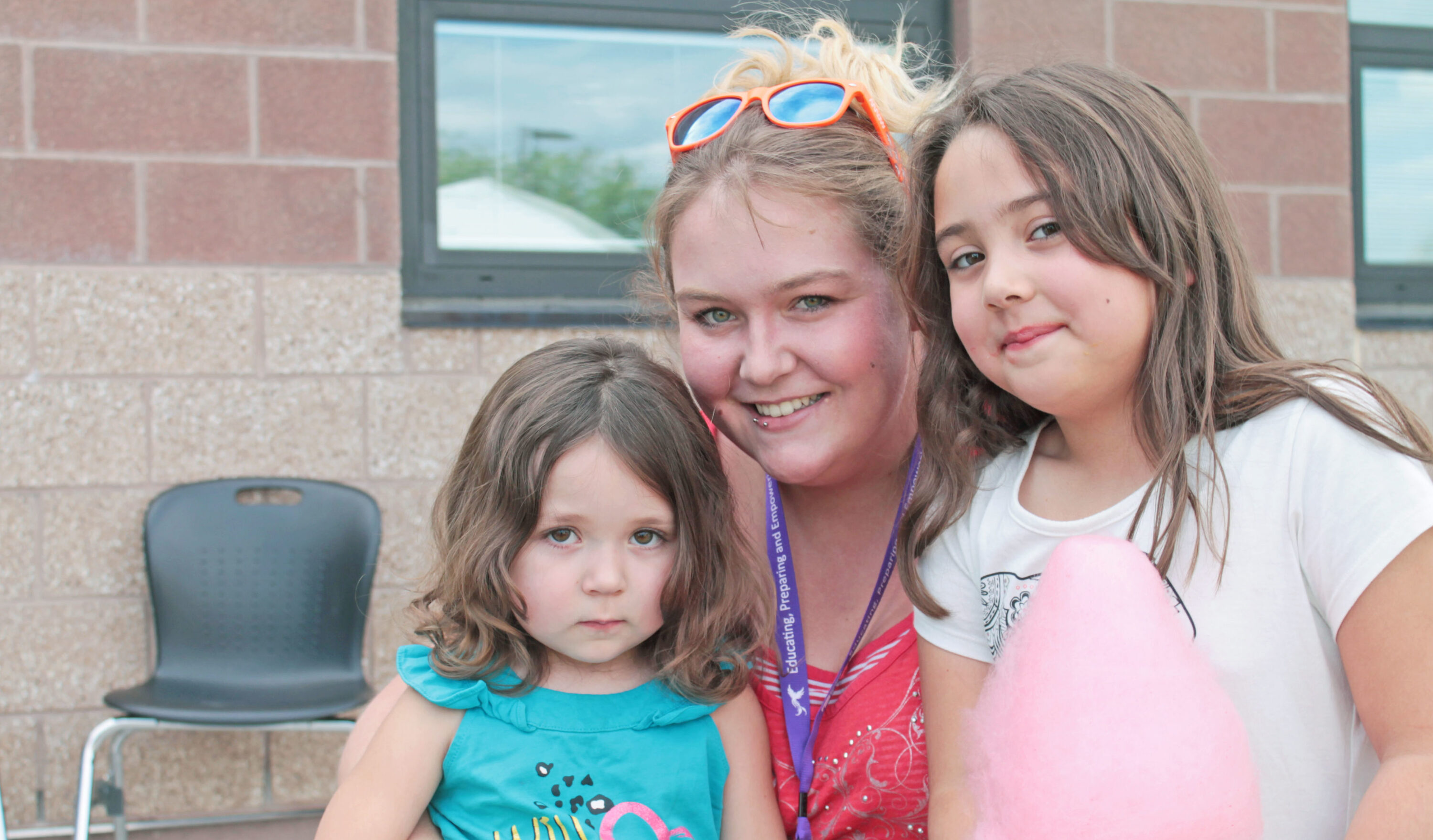 Smiling woman with two young girls outside.