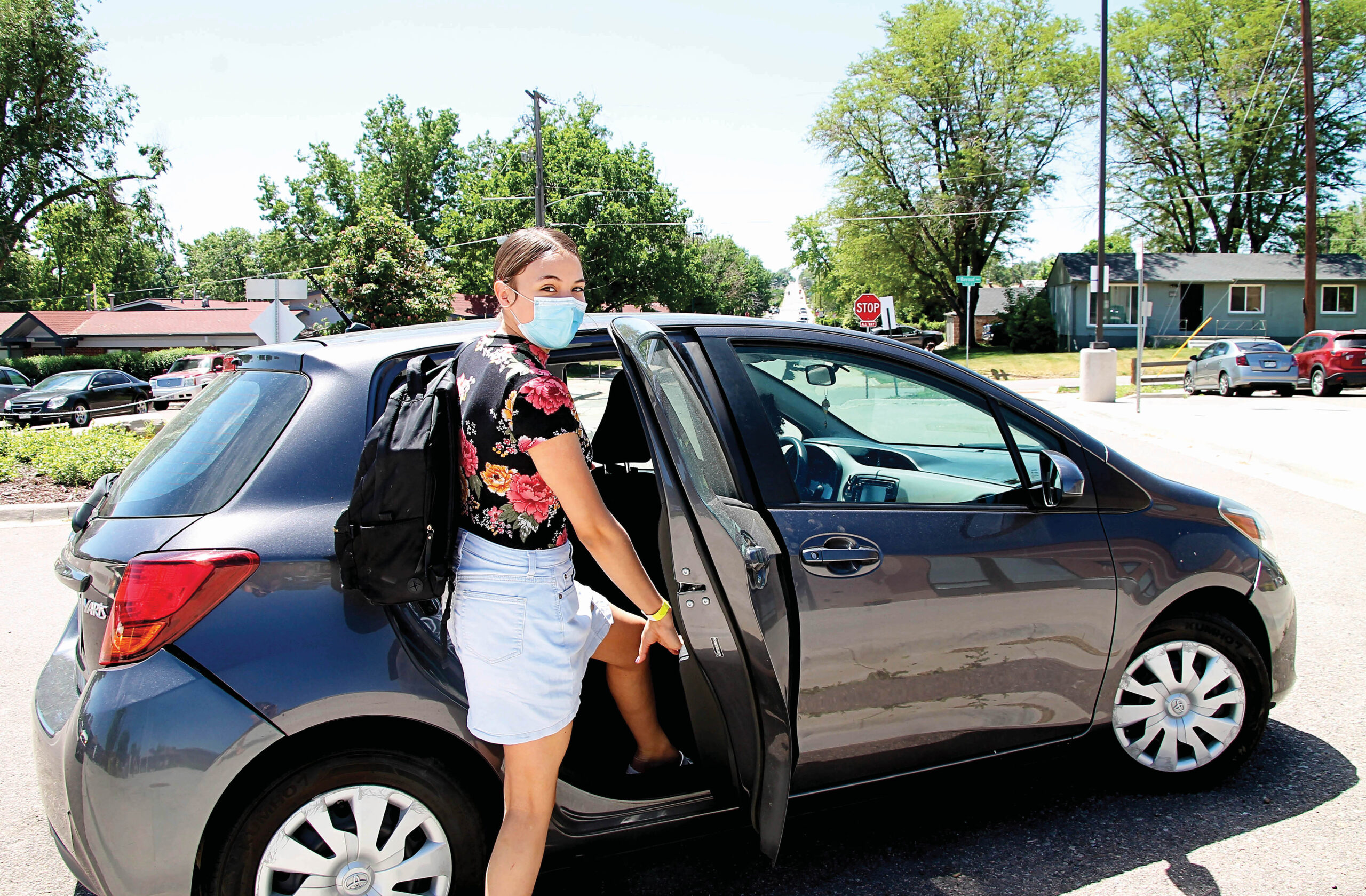 Person exiting parked car on a sunny day.