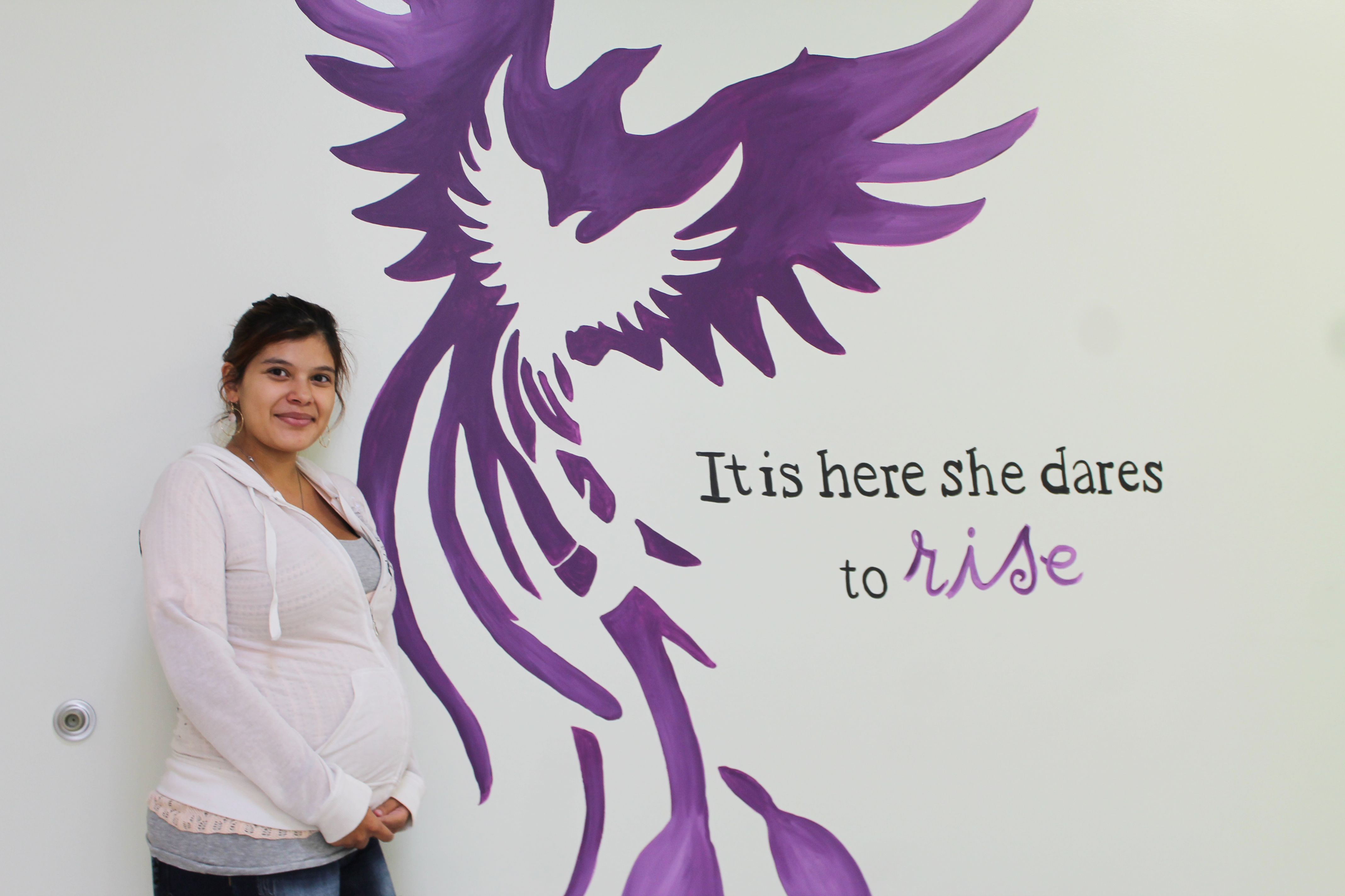 Pregnant woman beside inspirational mural