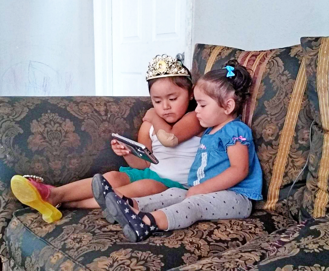 Children on sofa watching smartphone together.