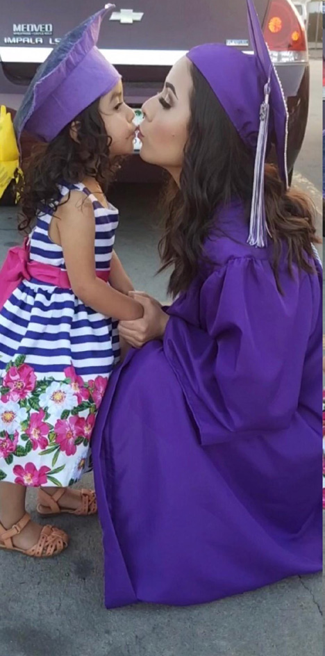 Graduate kisses child in flower dress.
