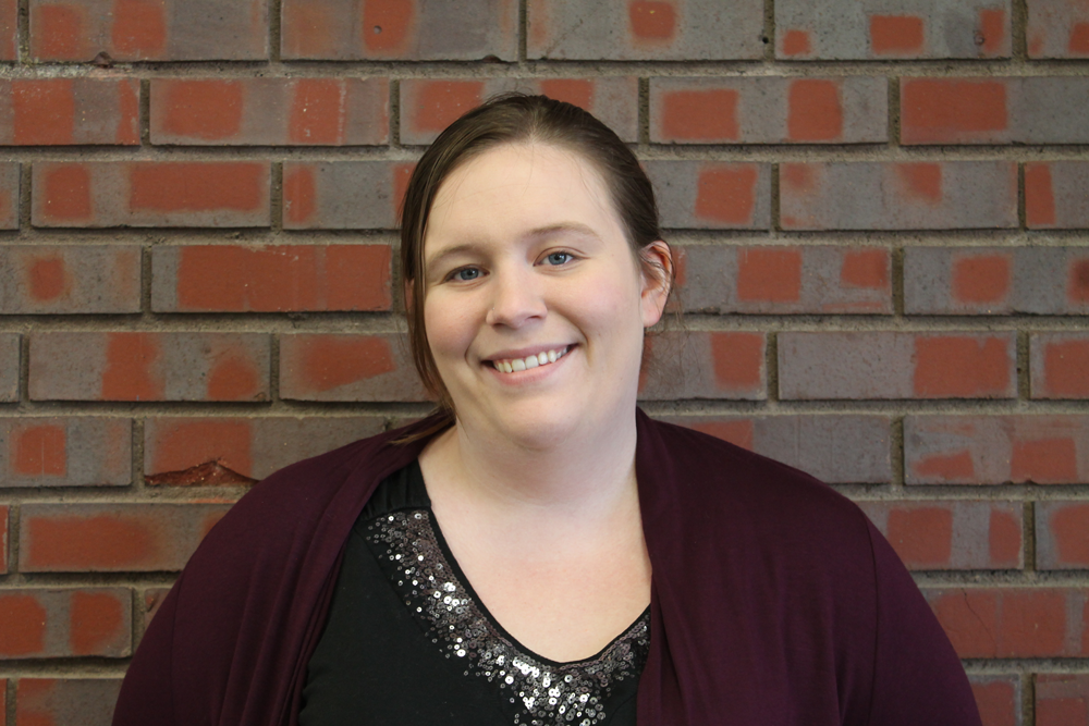 Woman smiling in front of brick wall
