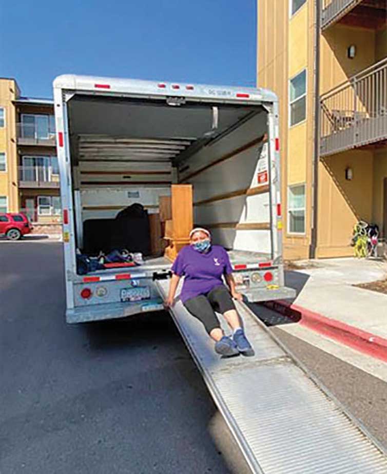 Person sitting on moving truck ramp.