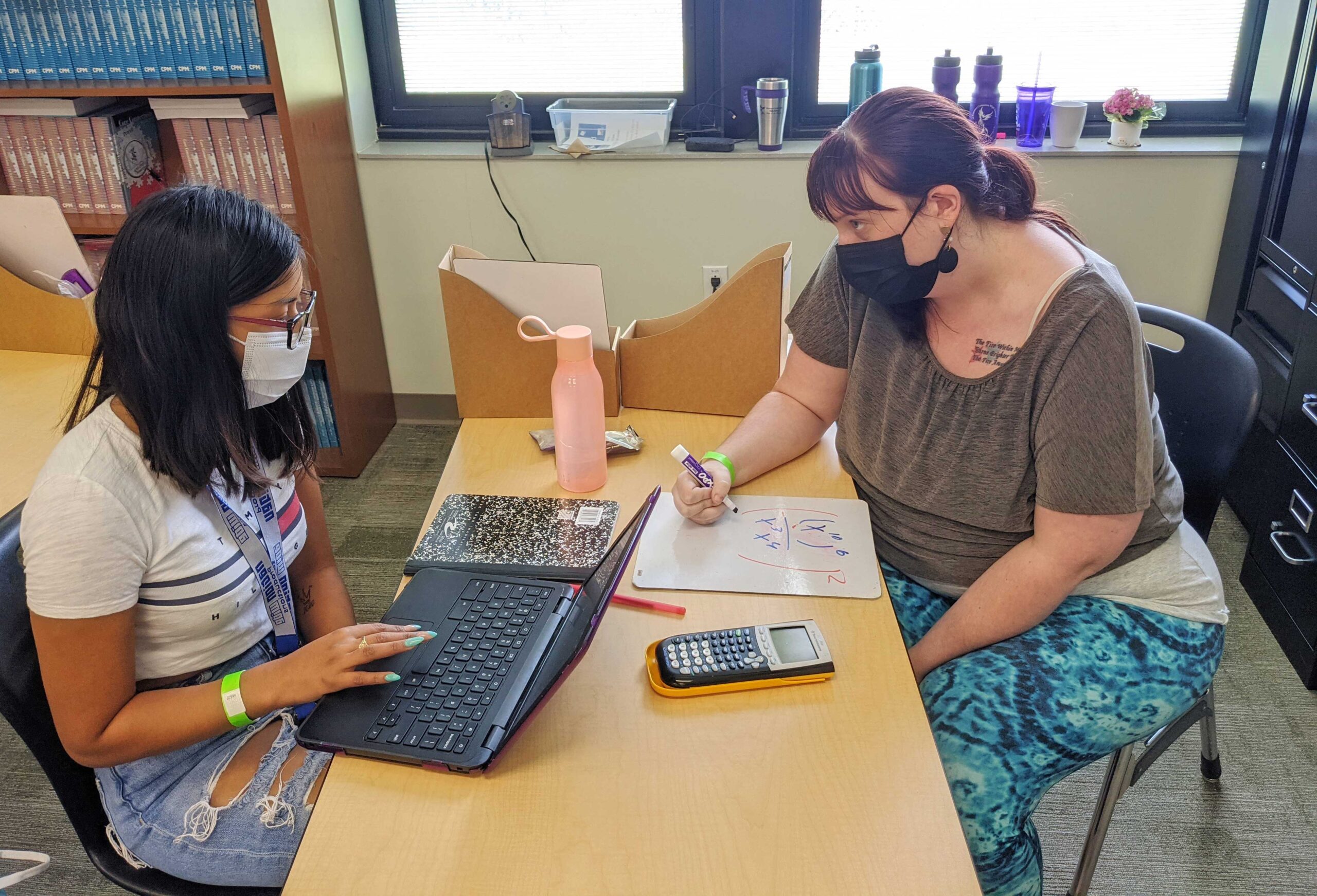 Two students working together on math problem.