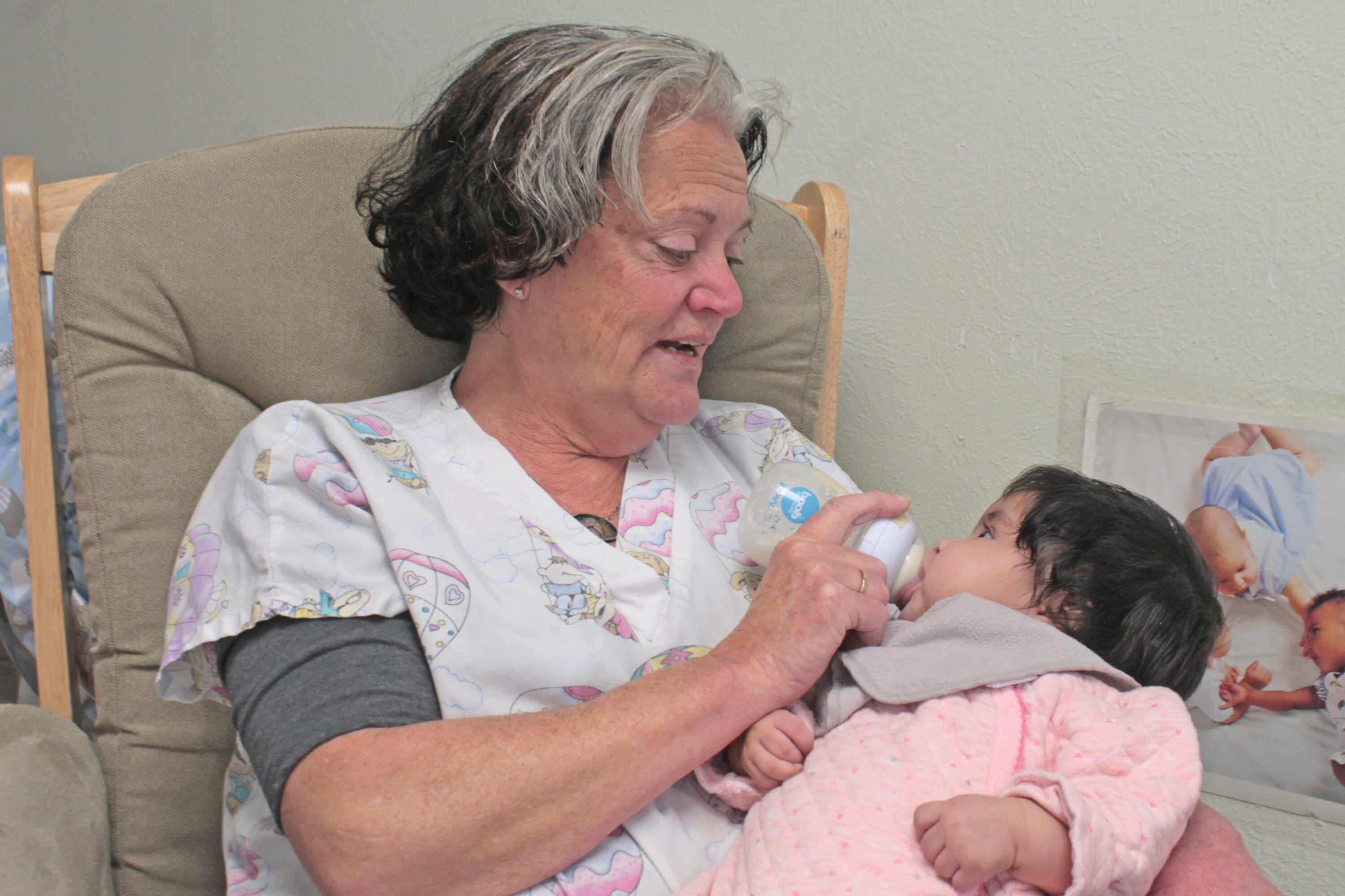 Woman feeding baby with bottle in chair.