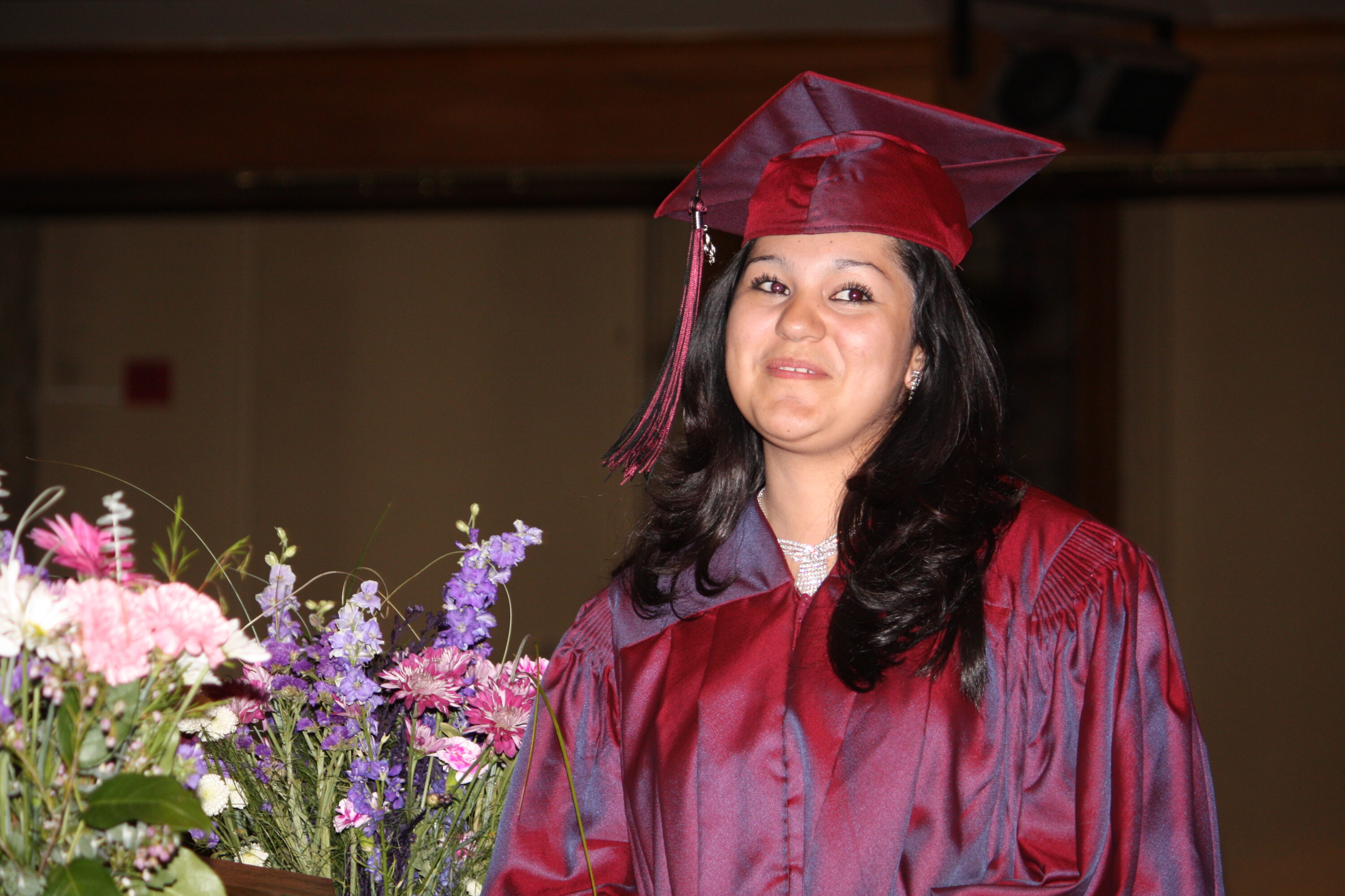 Graduate in cap and gown with flowers