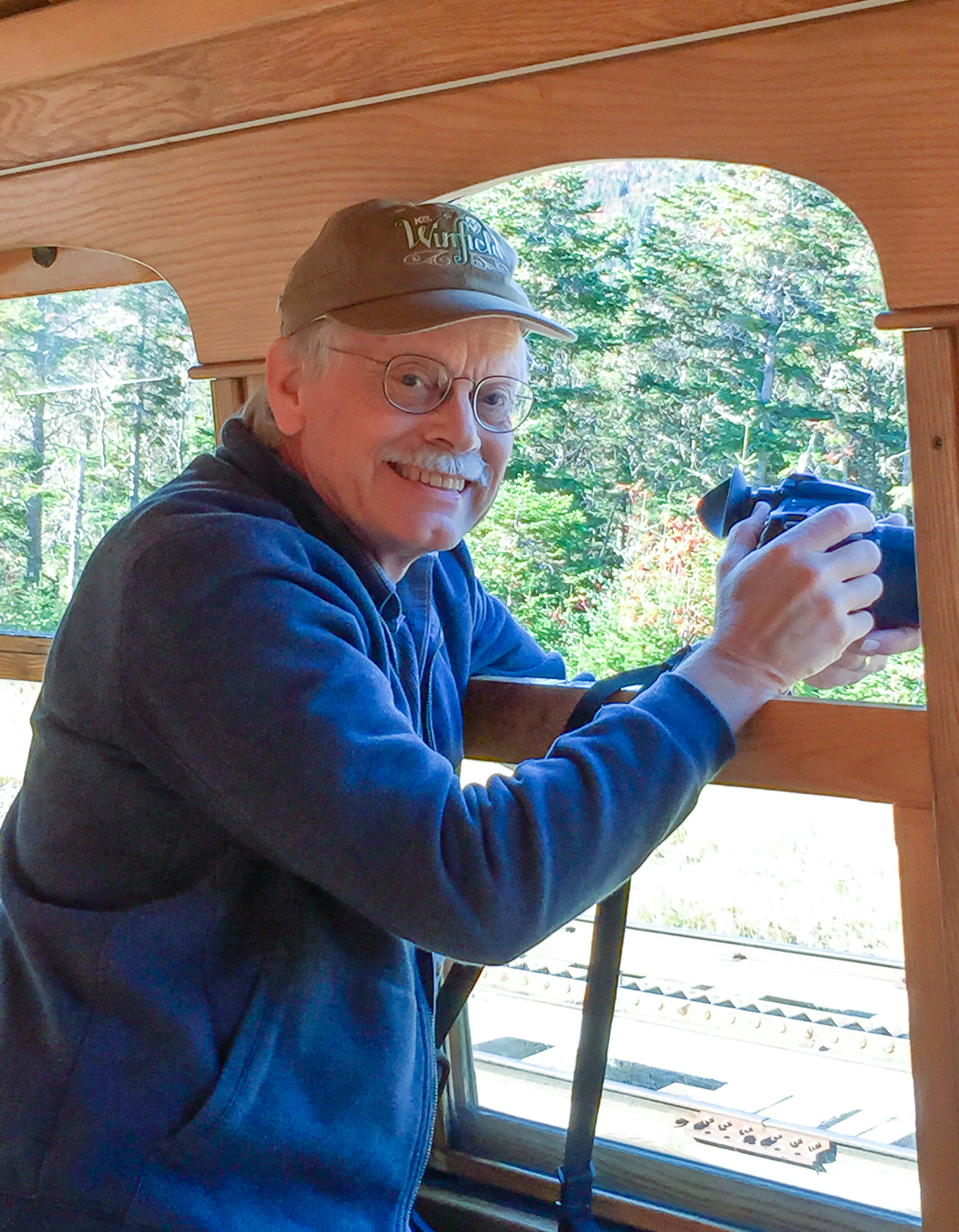 Man smiling with binoculars on train