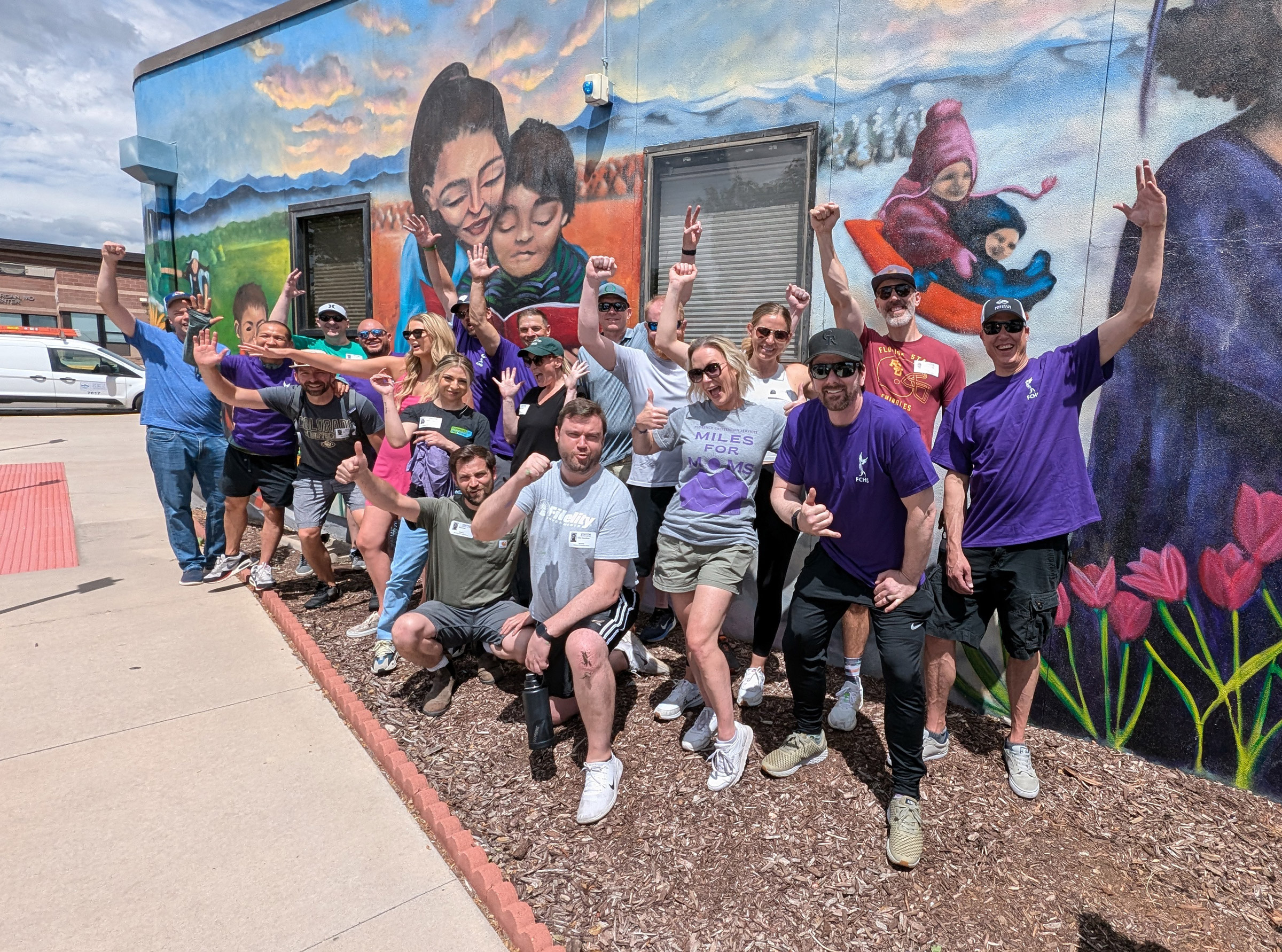 Group celebrates in front of vibrant mural wall.